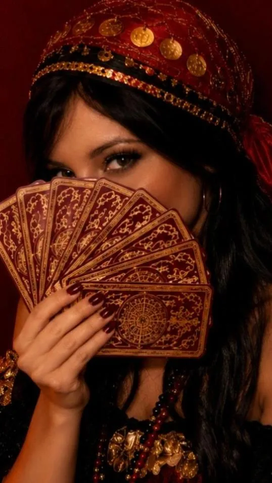 Mulher com lenço vermelho e dourado segurando cartas em leque