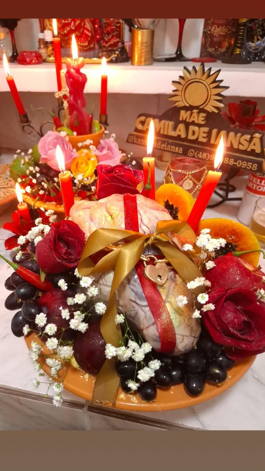 Altar de Mãe Kamilla de Iansã com velas, frutas, flores e o trabalho de amarração amorosa pronto