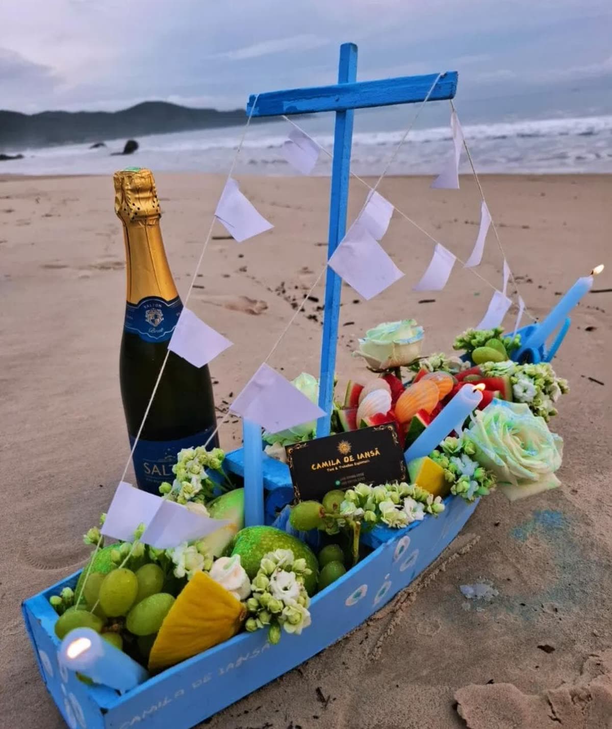 Barco de oferenda com flores, frutas e velas, na areia da praia, para a abertura de caminhos