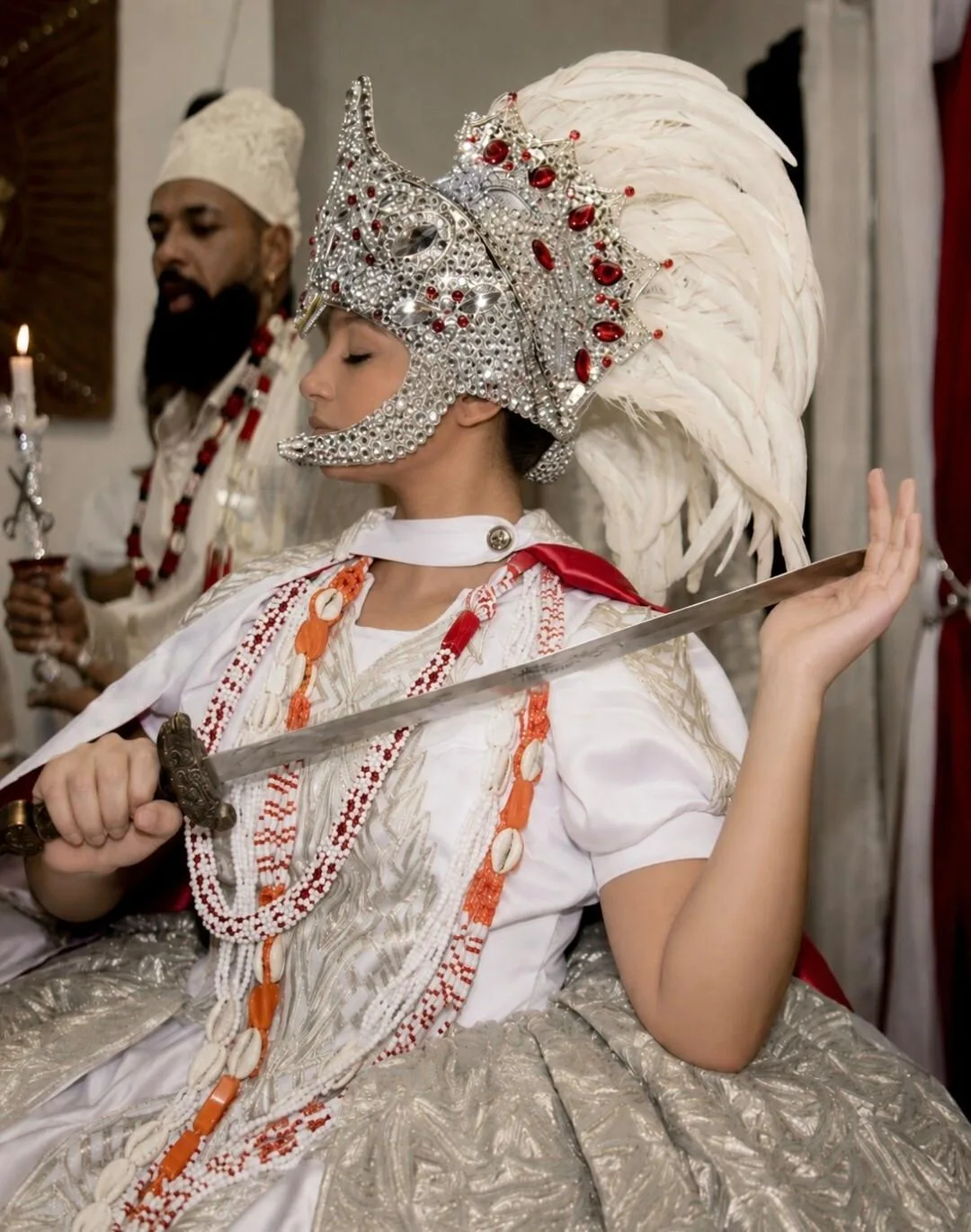 Mulher em traje cerimonial branco e prateado segurando uma espada