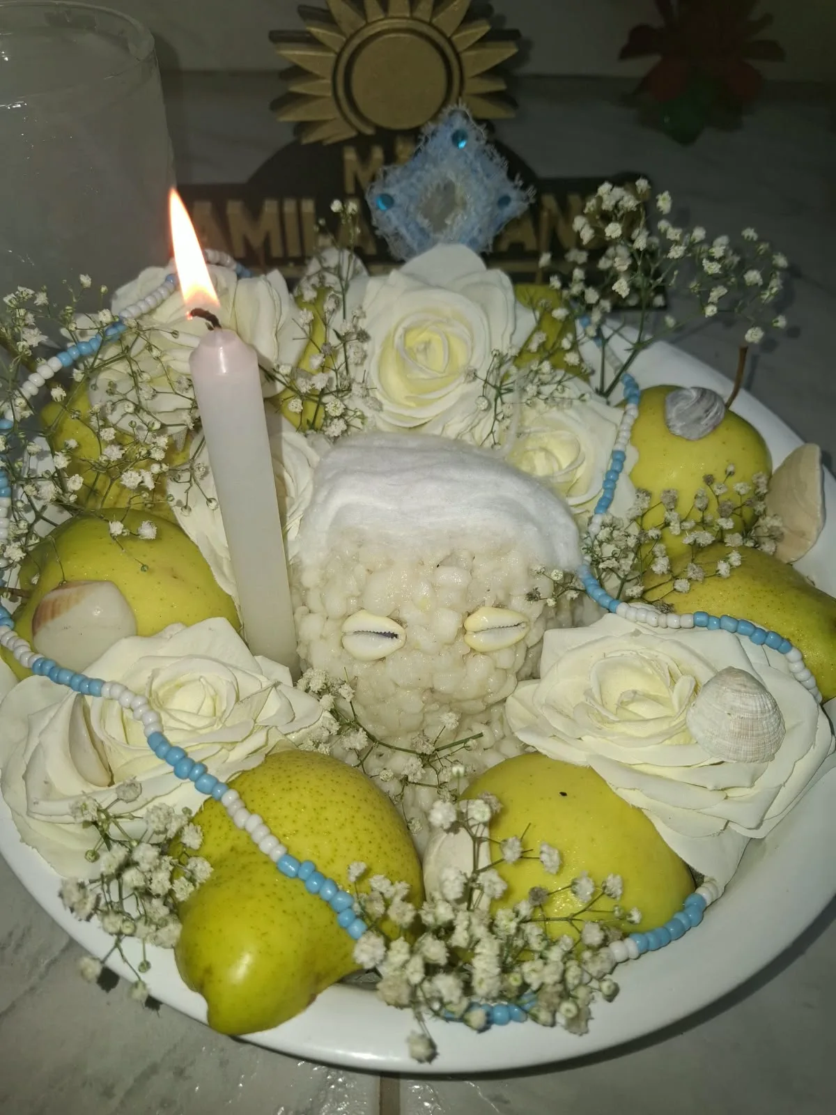 Trabalho espiritual branco com rosas, frutas, contas azuis e vela acesa